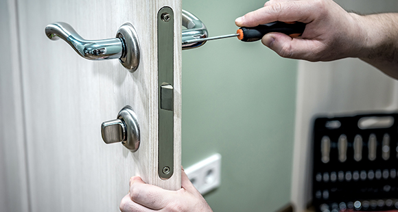 a person using a screwdriver to install a door lock