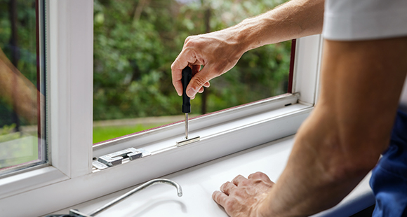 a person using a screwdriver to tighten up the security of a window frame