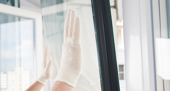 a gloved person placing a double glazed window pane into a uPVC frame