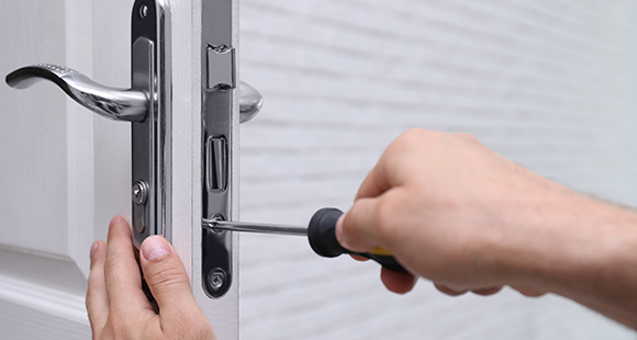 a person with a screwdriver installing a door handle 